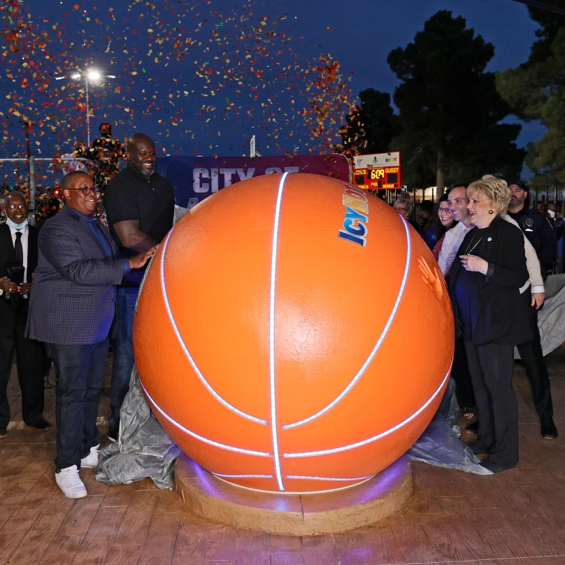 Shaquille O'Neil and other attendees at the inauguration of one of the Icy Hot Comebaq Courts. They are all standing next to a giant basket ball with the Icy Hot logo.